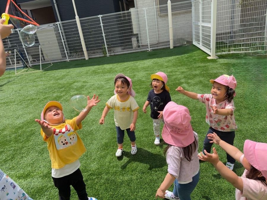 園庭でシャボン玉遊びを楽しむ子どもたち