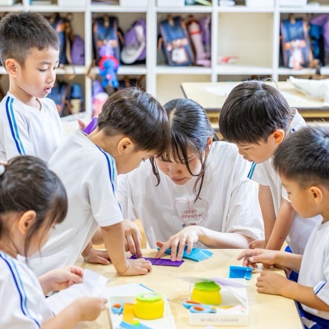 先生と一緒に折り紙制作に取り組む子どもたち